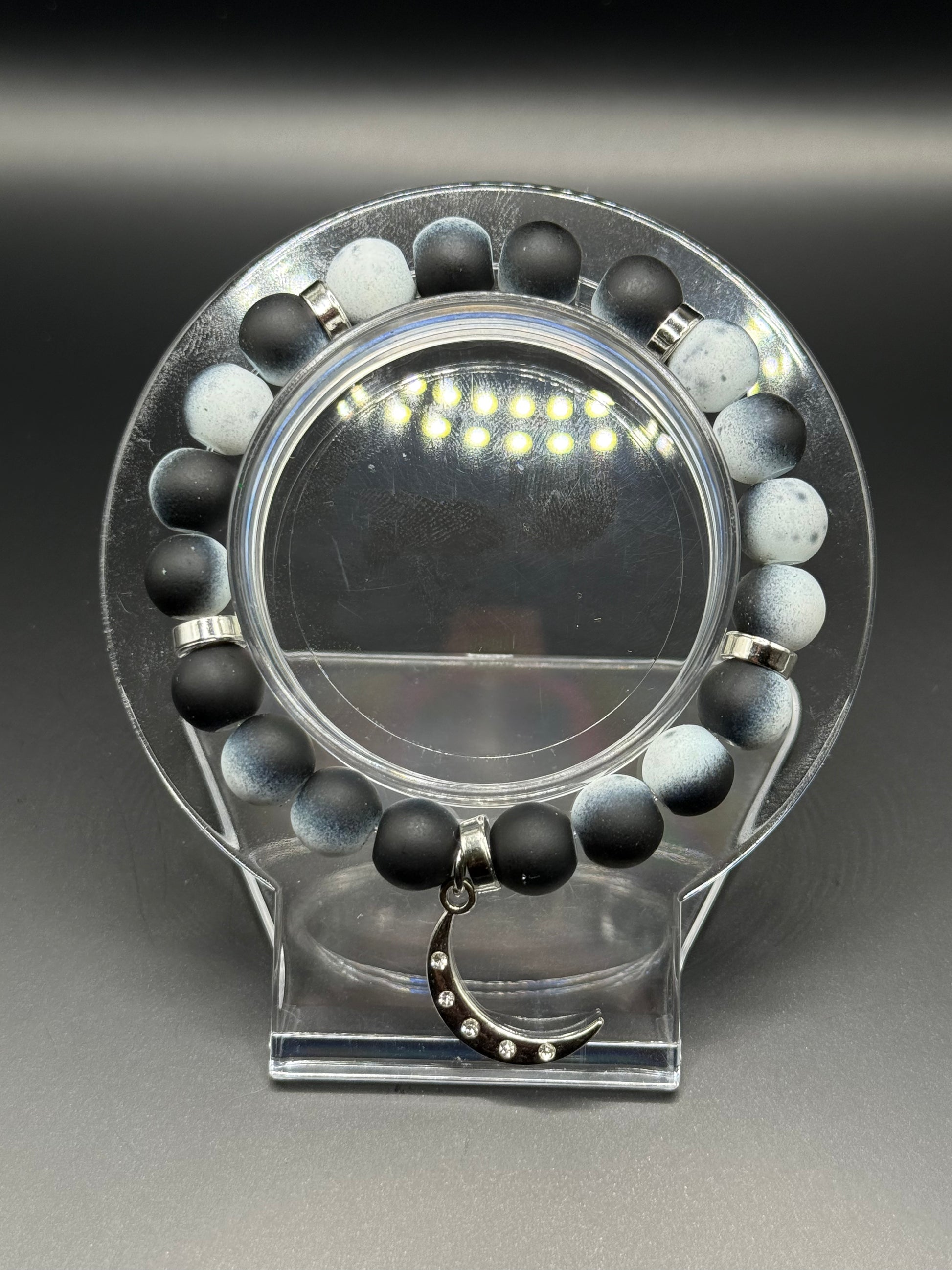 Blac and white beaded bracelet with a silver crescent moon shaped charm.