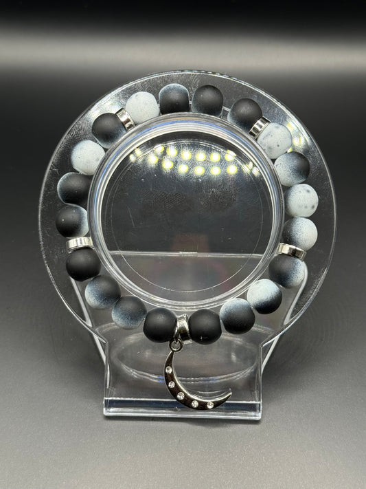 Blac and white beaded bracelet with a silver crescent moon shaped charm.